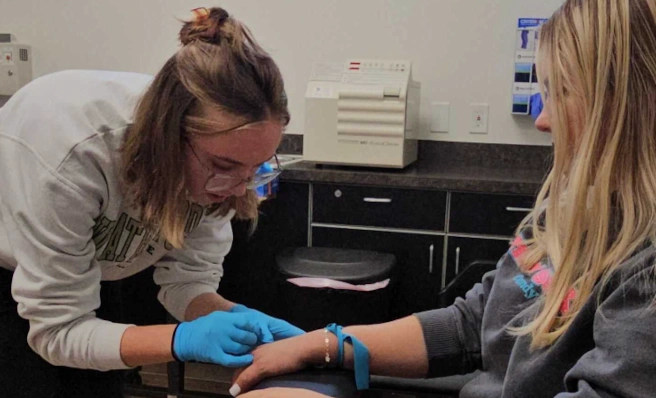 student training to apply an IV to a patient